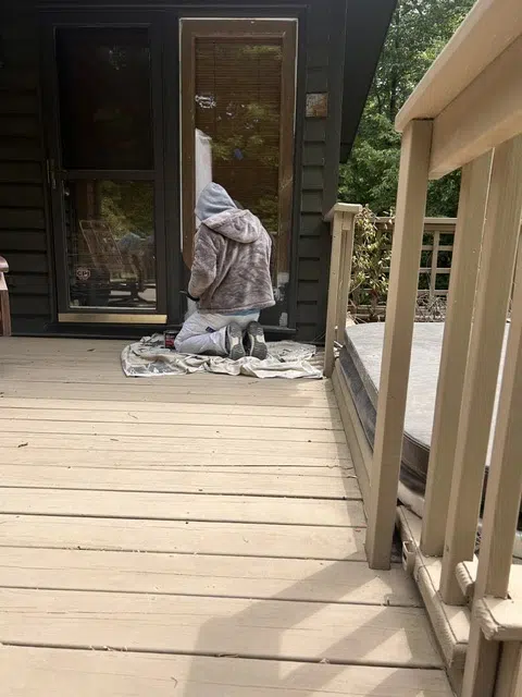 Painter kneeling on deck working on door frame — Father And Son Custom Painting in Raleigh